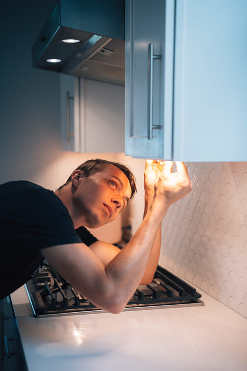 worker installing under cabinet lighting